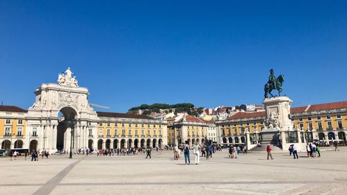 People at town square against clear blue sky