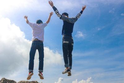 Low angle view of man jumping against sky