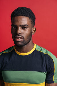 Portrait of young man standing against red background