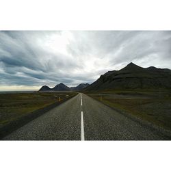 Road passing through landscape against cloudy sky