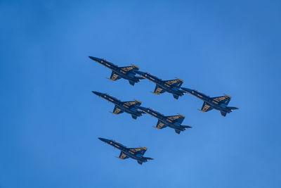 Low angle view of airplane flying against blue sky