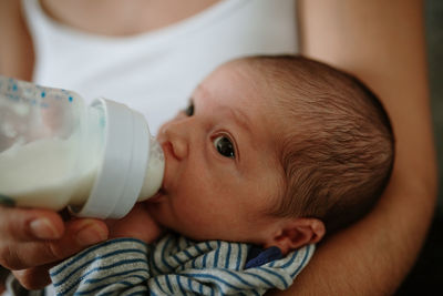 Midsection of woman feeding newborn son at home