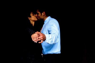 Side view of couple kissing while standing in darkroom