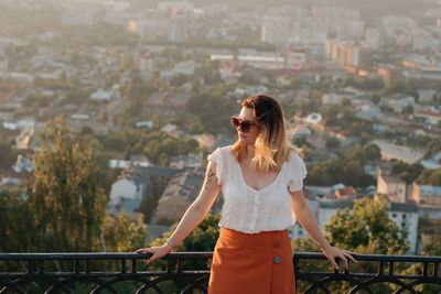 Full length of young woman standing on railing in city