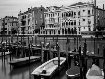 Boats moored in canal by buildings in city