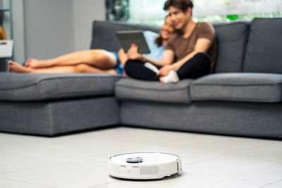 Midsection of woman using laptop while sitting on sofa at home