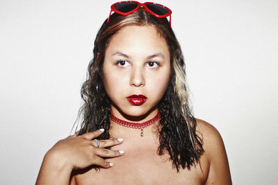 Young woman with sunglasses wearing choker necklace and red lipstick against gray background