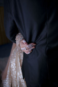 Midsection of bride holding groom at home