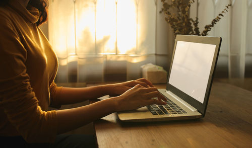 Midsection of woman using laptop on table