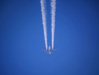 Low angle view of vapor trail against clear blue sky