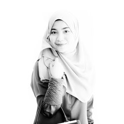 Portrait of smiling woman wearing hijab against white background
