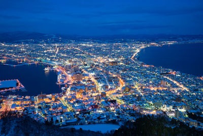 Aerial view of cityscape by sea at night