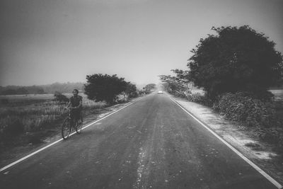 Road amidst trees against clear sky