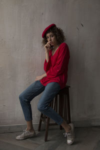 Portrait of smiling woman sitting against wall