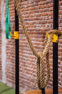 Rope hanging against brick wall