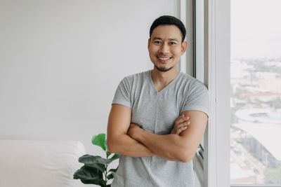 Portrait of young man sitting on bed at home