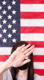 Unrecognized woman stretch out her hand and cover her face against american flag 