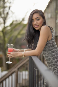 Young woman with a cocktail on her balcony