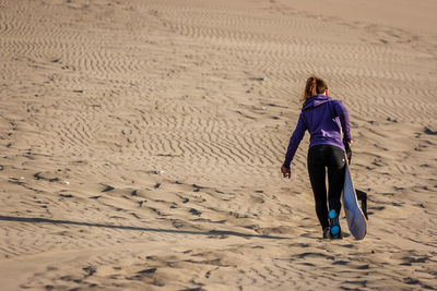 Rear view of woman walking on sand at beach