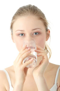 Portrait of a beautiful young woman drinking water against white background