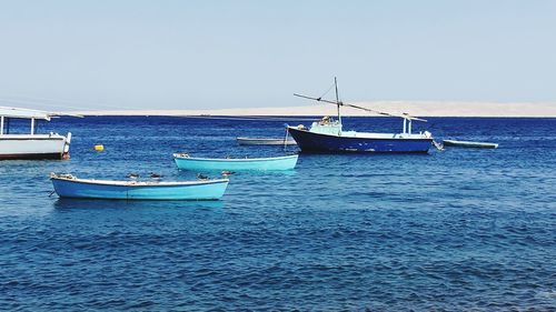 Sailboats moored on sea against clear sky