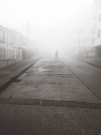 Man in city against sky during foggy weather