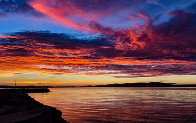 Scenic view of sea against dramatic sky during sunset