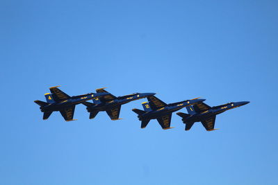 Low angle view of airplane flying against clear blue sky