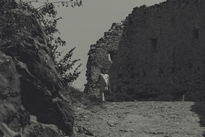 Woman standing on rock against sky