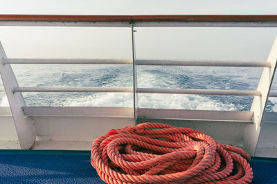 Close-up of a red rope on a dech by boat railing 