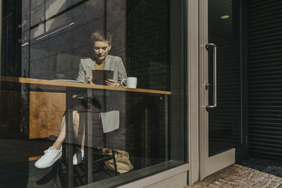 Woman holding digital table while sitting in cafe