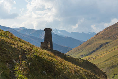 Scenic view of built structure on field against mountains and sky