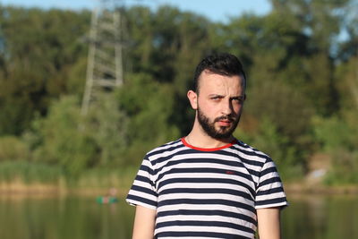 Portrait of young man standing against trees