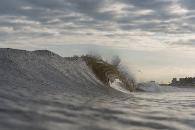 Sea waves splashing on shore against sky