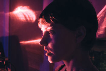 Close-up side view of woman in illuminated room at home
