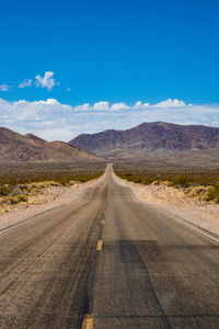 Road leading towards mountains against sky