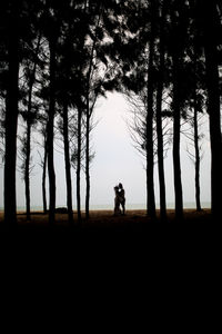 Silhouette man standing by tree on field against sky