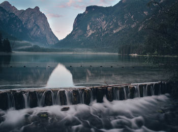 Scenic view of lake by mountains against sky