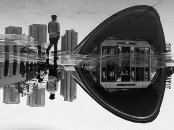 Reflection of woman photographing in city against sky