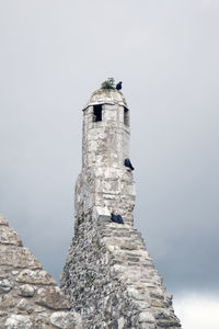 Low angle view of tower on rock against sky