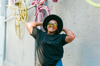 Portrait of young woman standing against wall