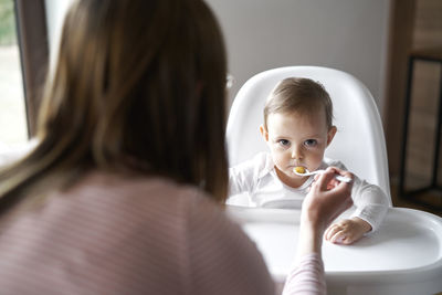 Mother feeding daughter at home