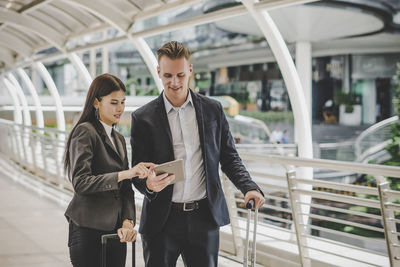 Colleagues using digital tablet while standing on footbridge