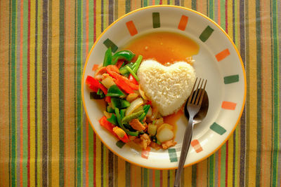 Stir fired vegetable with rice, heart shape serving on rainbow sheet table, lovely meal serving 