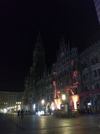 People walking on road against buildings at night