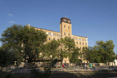 Trees and buildings against clear blue sky