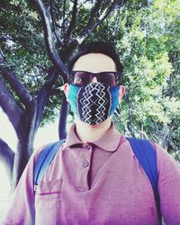 Portrait of young man wearing sunglasses against trees