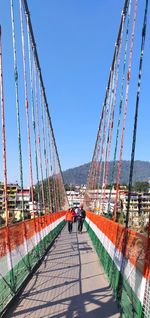 People walking on bridge against sky in city