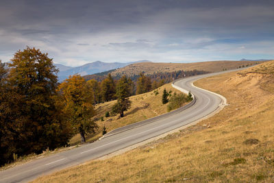Scenic view of road by mountains against sky