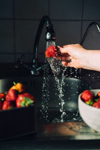 Woman hands washing fresh ripe strawberries in the kitchen. red vibrant strawberries under water 